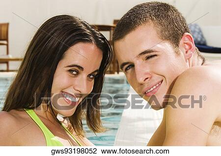 Stock Image - Portrait of a young couple smiling at the poolside. Fotosearch