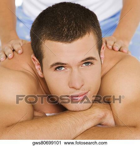 Stock Image - Portrait of a young man getting a shoulder massage. Fotosearch