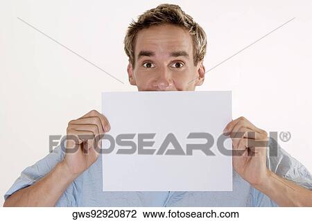 Portrait of a young man holding a blank placard in front of his mouth View Large Photo Image Stock Image - Portrait of a young man holding a blank placard in front of his mouth. Fotosearch