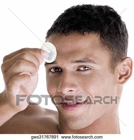 Stock Image - Portrait of a young man holding a condom. Fotosearch