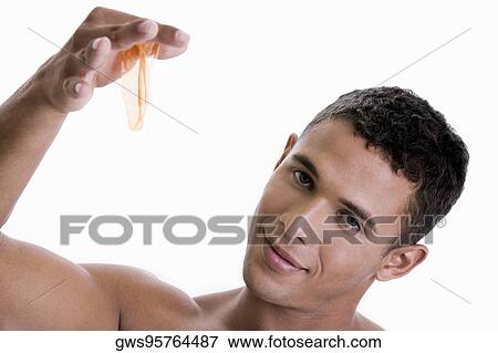 Portrait of a young man holding a condom View Large Photo Image Stock Photo - Portrait of a young man holding a condom. Fotosearch