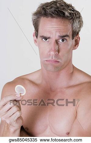 Stock Photography - Portrait of a young man holding a condom. Fotosearch