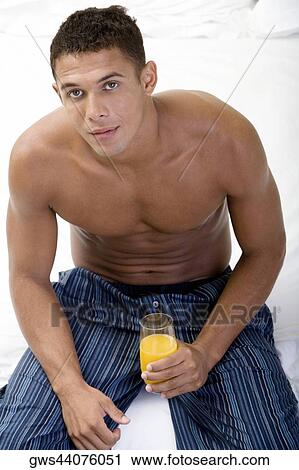 Portrait of a young man holding a glass of orange juice View Large Photo Image Stock Image - Portrait of a young man holding a glass of orange juice. Fotosearch