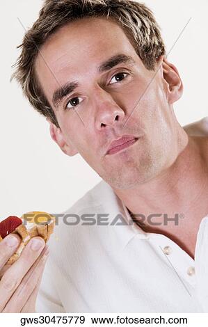 Portrait of a young man holding a strawberry tart View Large Photo Image Stock Photo - Portrait of a young man holding a strawberry tart. Fotosearch