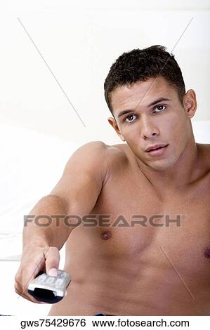 Stock Photograph - Portrait of a young man holding a remote control. Fotosearch
