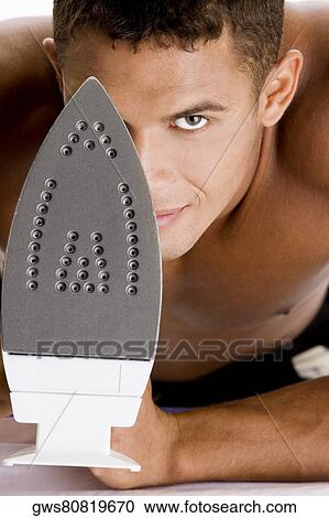 Portrait of a young man holding an iron View Large Photo Image Stock Image - Portrait of a young man holding an iron. Fotosearch