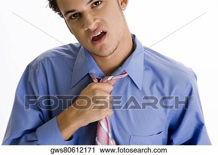 Stock Image - Portrait of a young man holding his tie. Fotosearch