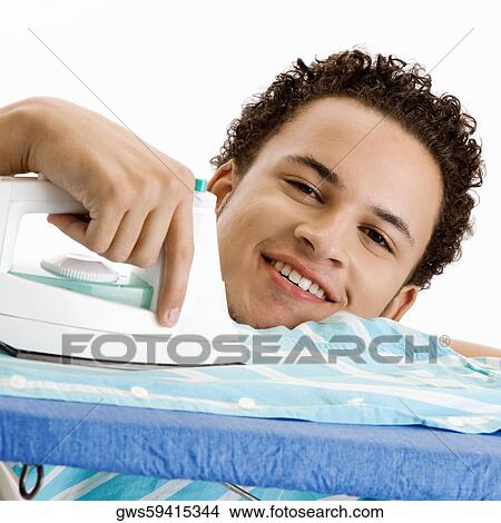 Portrait of a young man ironing his shirt View Large Photo Image Picture - Portrait of a young man ironing his shirt. Fotosearch