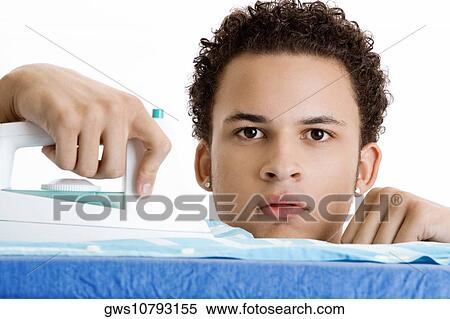 Stock Photography - Portrait of a young man ironing his shirt. Fotosearch