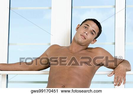 Stock Image - Portrait of a young man leaning against a window. Fotosearch