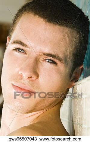 Stock Image - Portrait of a young man lying at the poolside. Fotosearch