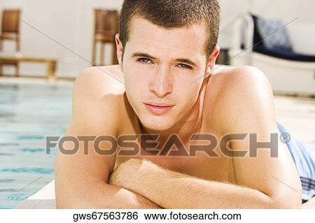 Portrait of a young man lying at the poolside View Large Photo Image Stock Photograph - Portrait of a young man lying at the poolside. Fotosearch