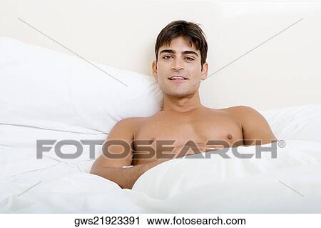Stock Image - Portrait of a young man lying on the bed. Fotosearch