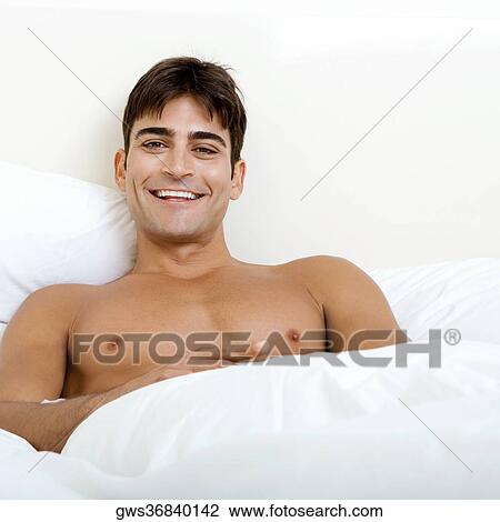 Portrait of a young man lying on the bed smiling View Large Photo Image Stock Image - Portrait of a young man lying on the bed smiling. Fotosearch