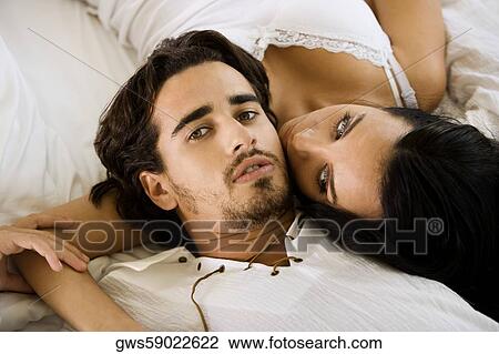 Stock Image - Portrait of a young man lying with a young woman on the bed. Fotosearch