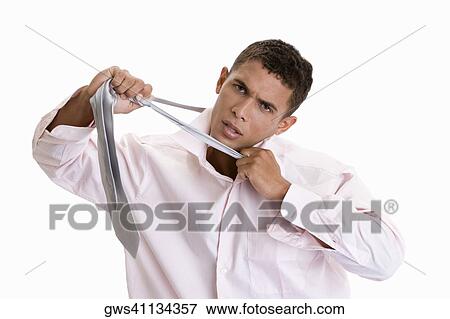 Stock Photo - Portrait of a young man pulling his tie. Fotosearch
