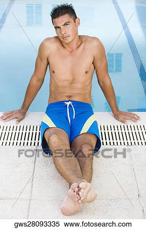 Stock Photography - Portrait of a young man sitting at the poolside. Fotosearch