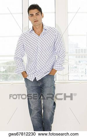 Stock Image - Portrait of a young man standing with his hands in his pockets. Fotosearch