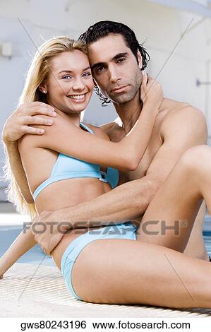 Portrait of a young woman and a mid adult man embracing at the poolside View Large Photo Image Stock Photograph - Portrait of a young woman and a mid adult man embracing at the poolside. Fotosearch