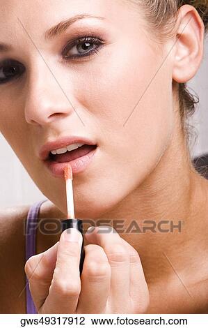 Stock Image - Portrait of a young woman applying lip liner. Fotosearch