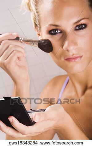 Portrait of a young woman applying blush with a brush View Large Photo Image Picture - Portrait of a young woman applying blush with a brush. Fotosearch