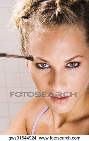 Picture - Portrait of a young woman applying eyeshadow. Fotosearch