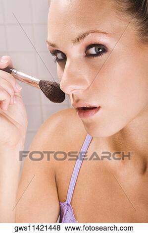 Portrait of a young woman applying blush with a brush View Large Photo Image Stock Photo - Portrait of a young woman applying blush with a brush. Fotosearch