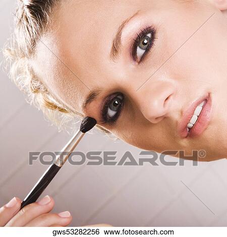Stock Photograph - Portrait of a young woman applying eyeshadow. Fotosearch