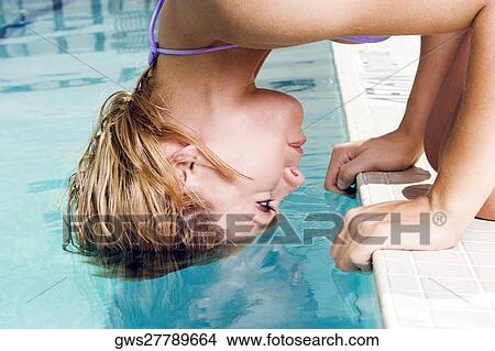 Portrait of a young woman bending forward with her hair in a swimming pool View Large Photo Image Picture - Portrait of a young woman bending forward with her hair in a swimming pool. Fotosearch