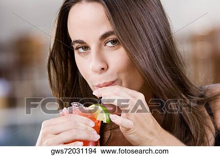 Portrait of a young woman drinking a cocktail View Large Photo Image Picture - Portrait of a young woman drinking a cocktail. Fotosearch