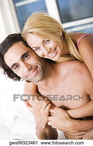 Stock Image - Portrait of a young woman embracing a young man from behind. Fotosearch