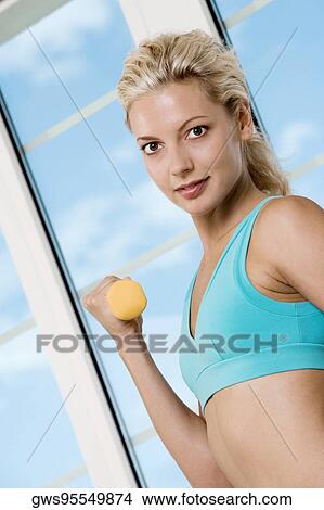 Picture - Portrait of a young woman exercising with dumbbells. Fotosearch
