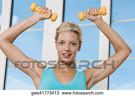 Portrait of a young woman exercising with dumbbells View Large Photo Image Stock Image - Portrait of a young woman exercising with dumbbells. Fotosearch
