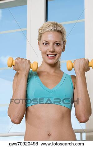 Portrait of a young woman exercising with dumbbells View Large Photo Image Stock Photo - Portrait of a young woman exercising with dumbbells. Fotosearch