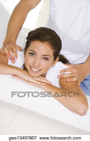 Stock Photo - Portrait of a young woman getting a shoulder massage. Fotosearch