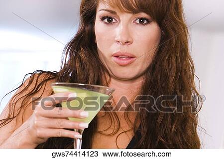 Portrait of a young woman holding a glass of martini View Large Photo Image Stock Image - Portrait of a young woman holding a glass of martini. Fotosearch