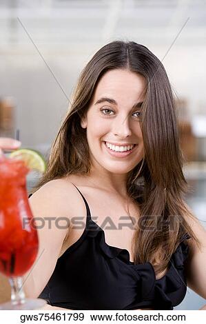 Portrait of a young woman holding a cocktail View Large Photo Image Stock Photo - Portrait of a young woman holding a cocktail. Fotosearch