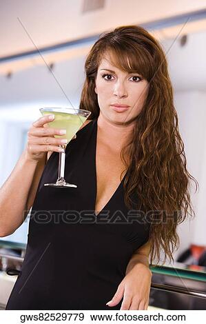 Portrait of a young woman holding a glass of martini View Large Photo Image Stock Photo - Portrait of a young woman holding a glass of martini. Fotosearch