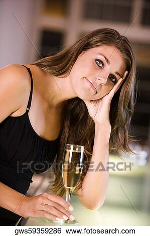 Portrait of a young woman holding a champagne flute View Large Photo Image Stock Photograph - Portrait of a young woman holding a champagne flute. Fotosearch