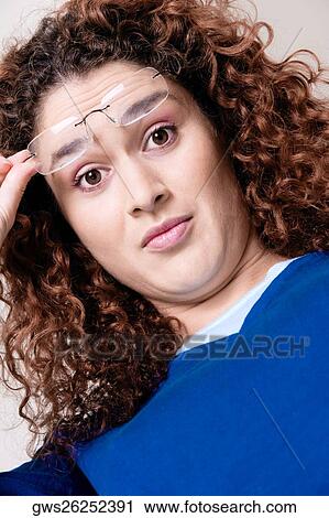 Stock Image - Portrait of a young woman holding her eyeglasses. Fotosearch