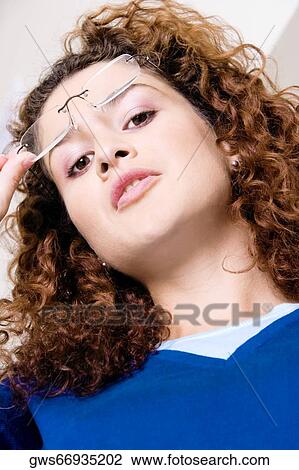 Portrait of a young woman holding her eyeglasses View Large Photo Image Stock Image - Portrait of a young woman holding her eyeglasses. Fotosearch