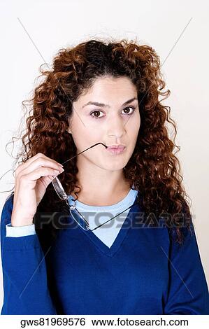 Portrait of a young woman holding her eyeglasses View Large Photo Image Stock Photograph - Portrait of a young woman holding her eyeglasses. Fotosearch