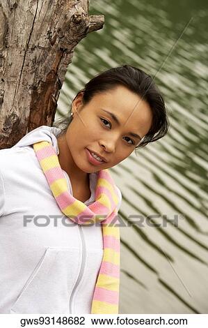 Portrait of a young woman leaning against a tree View Large Photo Image Stock Image - Portrait of a young woman leaning against a tree. Fotosearch