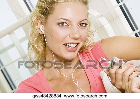 Portrait of a young woman listening to an MP3 player View Large Photo Image Picture - Portrait of a young woman listening to an MP3 player. Fotosearch