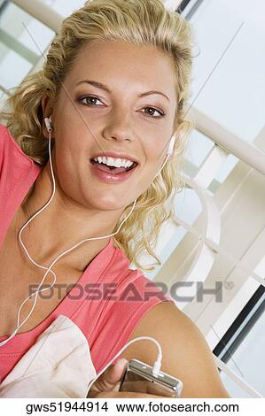 Portrait of a young woman listening to an MP3 player View Large Photo Image Picture - Portrait of a young woman listening to an MP3 player. Fotosearch