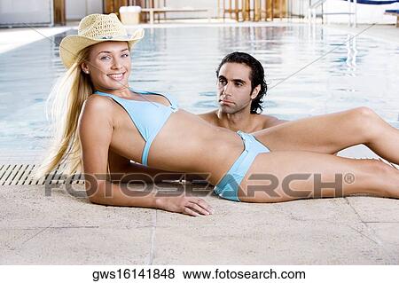 Portrait of a young woman lying down at the poolside with a mid adult man in the swimming pool View Large Photo Image Stock Photo - Portrait of a young woman lying down at the poolside with a mid adult man in the swimming pool. Fotosearch