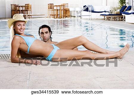 Portrait of a young woman lying down at the poolside with a mid adult man in the swimming pool View Large Photo Image Stock Photo - Portrait of a young woman lying down at the poolside with a mid adult man in the swimming pool. Fotosearch