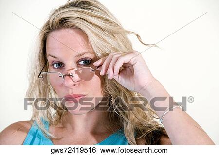 Portrait of a young woman peeking over her eyeglasses View Large Photo Image Stock Photograph - Portrait of a young woman peeking over her eyeglasses. Fotosearch