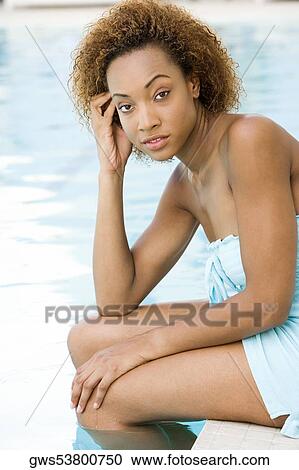 Portrait of a young woman sitting at the edge of a swimming pool with her hand on her temple View Large Photo Image Stock Image - Portrait of a young woman sitting at the edge of a swimming pool with her hand on her temple. Fotosearch