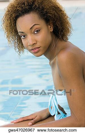 Portrait of a young woman sitting at the edge of a swimming pool View Large Photo Image Stock Photo - Portrait of a young woman sitting at the edge of a swimming pool. Fotosearch